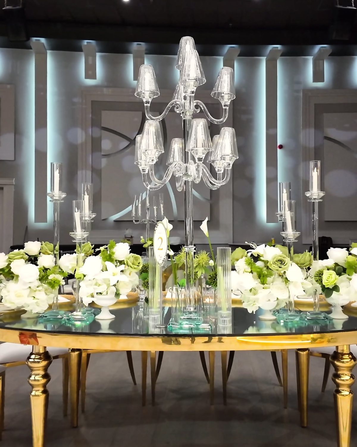 Long gold-and-glass head table lined with white florals and crystal candelabras